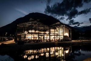 a large glass building with a mountain in the background at Såndgøld Alpine Glamping in Campo Tures