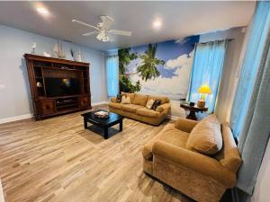 a living room with two couches and a flat screen tv at Tropical Riverfront Paradise - Gorgeous Sunset Views in Merritt Island