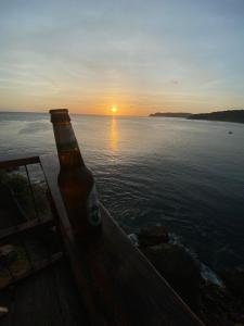 una botella de cerveza sentada en una mesa de madera junto al océano en Lulu Mocktails en San Juan del Sur