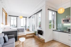 Home Suite Home Gran Via في مدريد: غرفة معيشة مع أريكة ومطبخ مع نوافذ