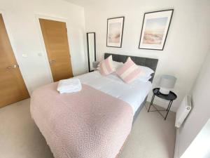 a bedroom with a large bed with pink pillows at Stunning 2 bed, water front Poole Quay Apartment. in Hamworthy