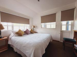 Schlafzimmer mit einem großen weißen Bett und Fenstern in der Unterkunft Hotel Geronimo in Pucón