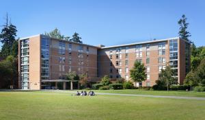 un gruppo di persone sedute su un prato di fronte a un edificio di Pacific Spirit Hostel a Vancouver