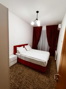 - une petite chambre avec un lit et des rideaux rouges dans l'établissement Vake Park Apartment, à Tbilissi