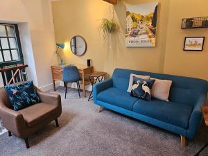 a living room with a blue couch and a chair at The Well House Boutique Cottage Hebden Bridge Central in Hebden Bridge