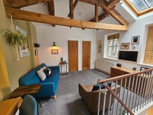 a living room with a blue couch and a tv at The Well House Boutique Cottage Hebden Bridge Central in Hebden Bridge