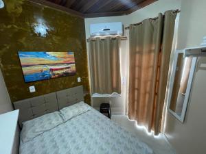 a small bedroom with a bed and a painting on the wall at Casa Galaxy in Boa Vista