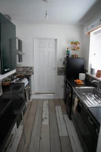 kuchnia z białymi drzwiami i drewnianą podłogą w obiekcie Sara’s Apartment w mieście Seaham