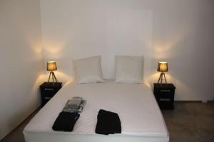 1 dormitorio con 1 cama blanca y 2 lámparas en Gîte Les Oliviers, en Saou