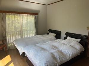 2 camas individuales en un dormitorio con ventana en 那須リゾートMomiji 貸切, en Nasu