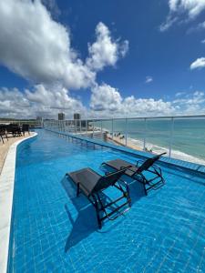 a swimming pool with two lounge chairs on the beach at RN Studio Maceió Apto 302 in Maceió
