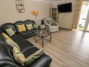 uma sala de estar com um sofá de couro preto e uma mesa em Meadow View em Laugharne