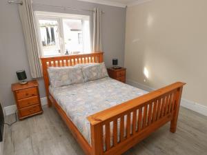 um quarto com uma cama de madeira e uma janela em Meadow View em Laugharne