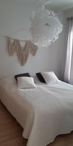 1 dormitorio con cama blanca y lámpara de araña en Pikiruukin helmi, en Kokkola