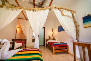 a bedroom with two beds and curtains in a room at Beach Break Hotel & Surf Camp de Playa Venao in Playa Venao