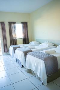 a hotel room with three beds and a window at Pousada Aeroporto in Parnaíba