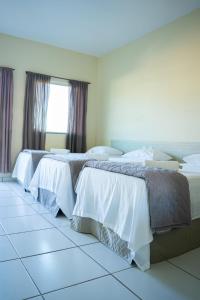 Pousada Aeroporto في بارنايبا: سريرين في غرفة بيضاء ورمادية
