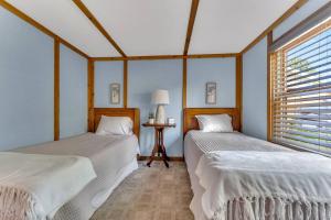 two twin beds in a room with a window at Peaceful Lakefront Cabin Retreat with Hot Tub! 