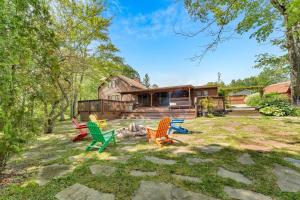 a group of chairs sitting in a yard in front of a house at Peaceful Lakefront Cabin Retreat with Hot Tub! 