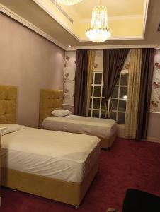 ein Hotelzimmer mit 2 Betten und einem Kronleuchter in der Unterkunft Botanical Garden Vacation House in Liwa