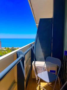 a blue chair on a balcony with a view of the ocean at Batumi Rest Apartament in Batumi