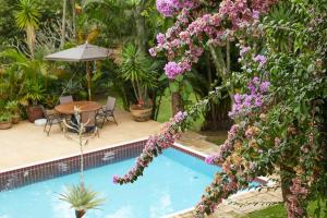 uma piscina com mesa e flores roxas em Casa Pinheiral em Bragança Paulista