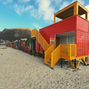 a row of colorful beach huts on the beach at Ben Your Friend Youth Foundation in Cape Town