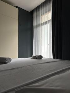 a bed with two towels on it in front of a window at A-Y Apartments P A4 in Tbilisi City