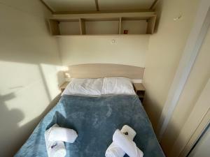uma pequena cama num pequeno quarto com toalhas em Borostyán horgásztó & pihenőpark em Mende