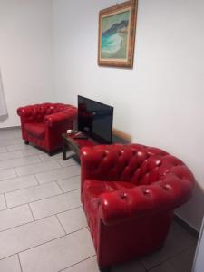 a living room with two red leather couches and a tv at Casa Surunova in Naples