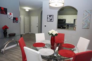 uma sala de jantar com uma mesa de vidro e cadeiras vermelhas em WH205B 3 BR Windsor Hills Condo! em Orlando