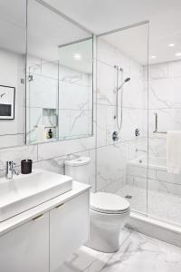 a white bathroom with a toilet and a shower at Award winning 1 bedroom apartment - extended stay in Calgary