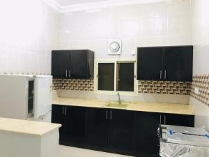 cocina con armarios negros y nevera blanca en راسيات الحمدانية - Hotel Rasiyat en Yeda