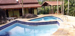 una piscina con azulejos azules en un patio en Riacho Doce Pousada, en São Francisco Xavier