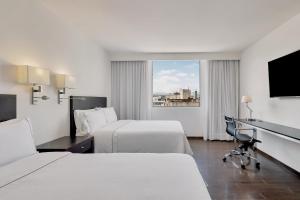 a hotel room with two beds and a desk at Fiesta Inn Insurgentes Sur in Mexico City