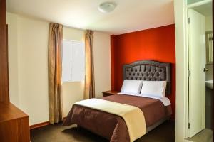 1 dormitorio con 1 cama con pared de color naranja en REAL MARQUEZ, en Trujillo