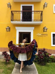 una mujer con un vestido parada frente a un edificio amarillo en REAL MARQUEZ, en Trujillo