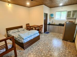 a bedroom with a bed and a table and a kitchen at Sunny Smiles in Mangalore
