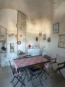 een tafel en stoelen in een kamer met een stenen muur bij La Maison di Paola in Ostuni
