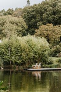 two benches sitting on a dock next to a lake at Gîtes du Bulz, en pleine forêt proche de la mer in Pleyber-Christ
