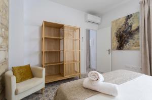1 dormitorio con cama, silla y estante para libros en Apartamento El Mural, en Jerez de la Frontera
