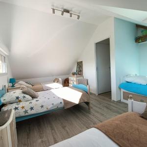 2 camas en una habitación con paredes azules en L'écurie d'antan, en Hautot-Saint-Sulpice