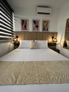 a bedroom with a large white bed with two lamps at GRAND HOTEL JAMUNDI in Jamundí
