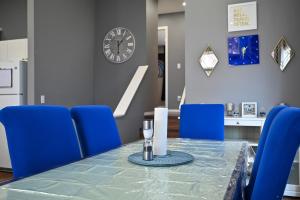 uma sala de jantar com uma mesa com cadeiras azuis e um relógio em 12 Spacious Home W Ac, Crib, Garage, By Airport em Calgary