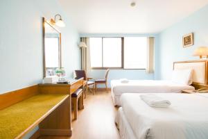 a hotel room with two beds and a desk at Wish Inn Chidlom By GO INN - วิช อินน์ ชิดลม in Makkasan