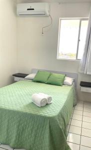 1 dormitorio con 1 cama verde y 2 toallas en Costa Dourada, en São José da Coroa Grande