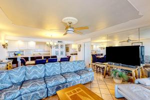 a living room with a blue couch and a flat screen tv at Ocean Vista #1101 in South Padre Island