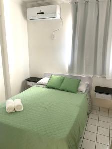 Un dormitorio con una cama verde con toallas. en Costa Dourada, en São José da Coroa Grande