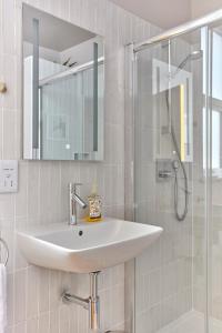 La salle de bains blanche est pourvue d'un lavabo et d'une douche. dans l'établissement Spacious beach front apartment with stunning sea views, à Deal