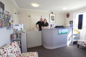 a man and woman standing at a counter in a store at Matariki Motor Lodge in Te Awamutu